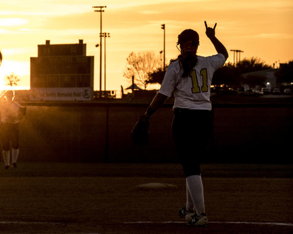 Silhouette of a UM-Dearborn softball player at twilight. 