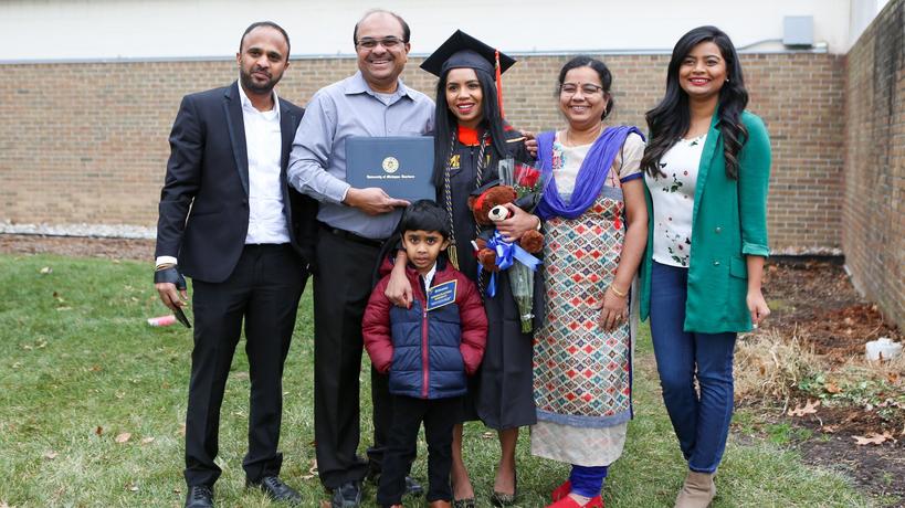 A graduate student with her family and friends at a commencement cermony