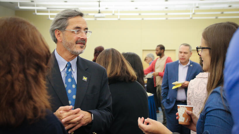 Chancellor Grasso talking with a staff member at a gathering.