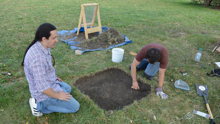 UM-Ann Arbor PhD student Nick Trudeau supervises UM-Dearborn undergraduate Will Smith as he cleans up the profile of an excavation unit.