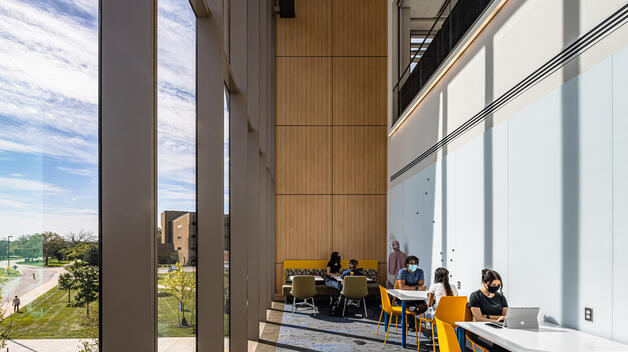 Students study next to huge multi-story windows in the Engineering Lab Building.
