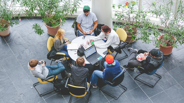 An aerial view of students gathering around a table to collaborate in the breezy atrium of the CASL building.